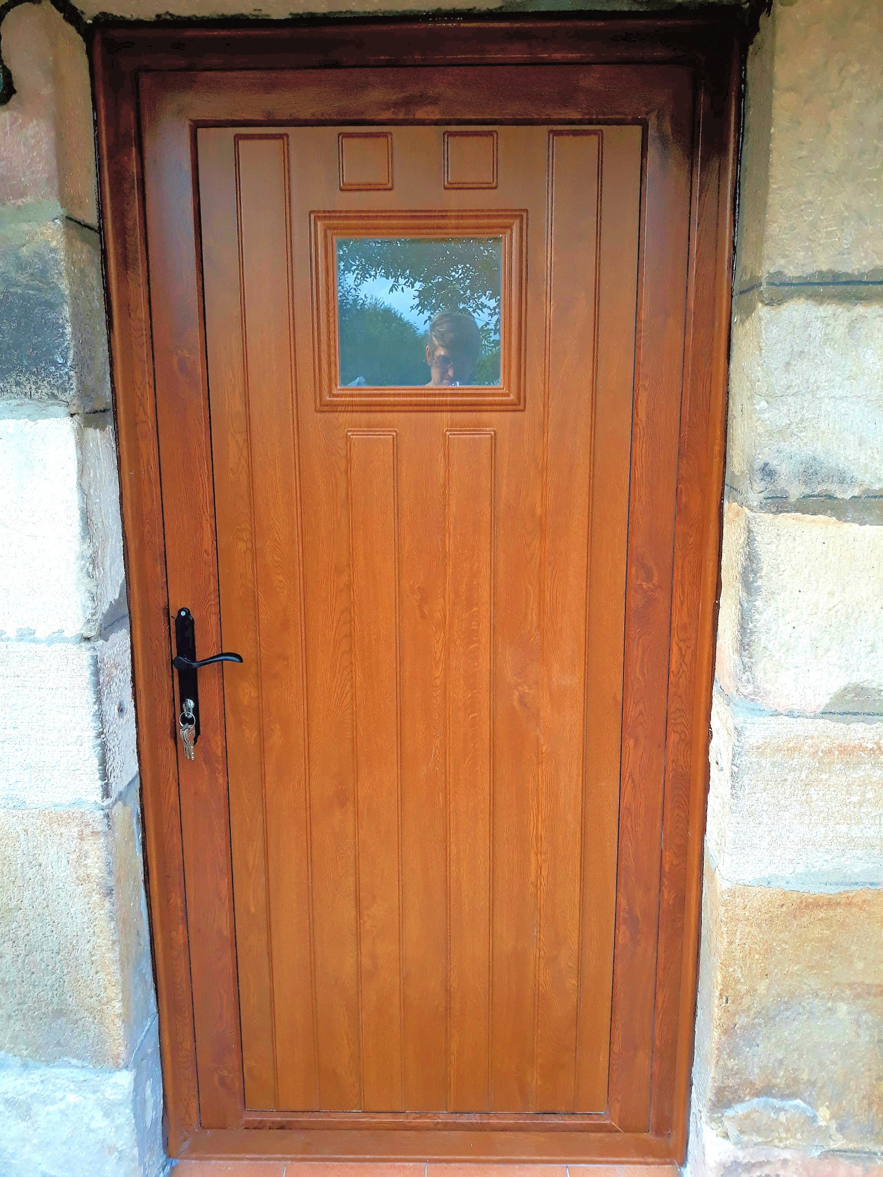 Puerta de entrada en PVC con panel en imitación madera con vidrio de seguridad en Cantabria