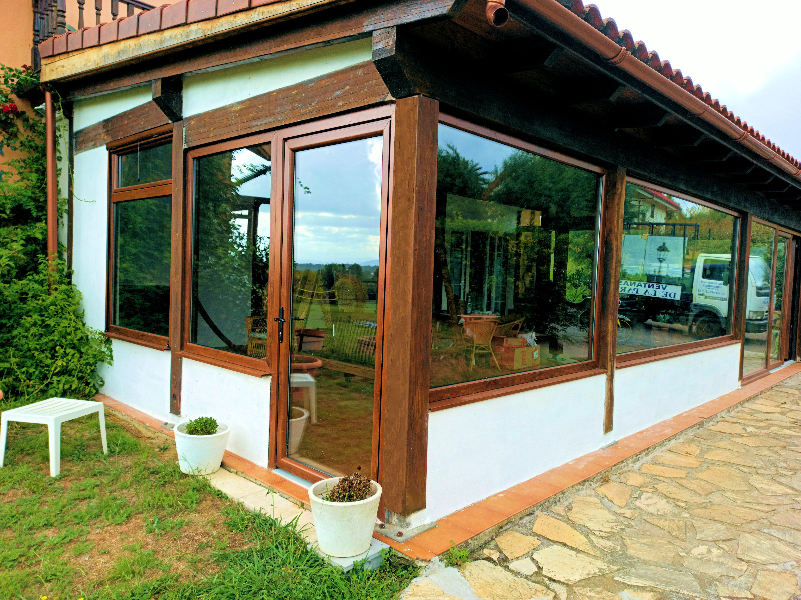 Cerramiento PVC compuesto por puertas, ventanas y fijos en imitación madera instalado en Cantabria