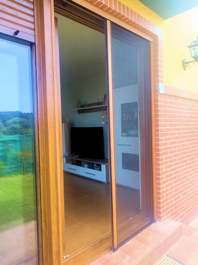 Oscilo paralela en imitación madera en PVC con mosquitera lateral instalado en Ajo, Cantabria 
